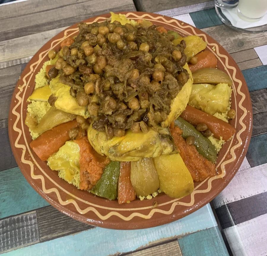 Couscous dressé sur un plat en terre avec poulet, légumes en gros morceaux et pois chiches