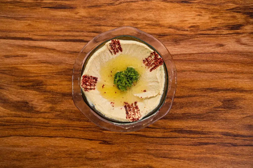Houmous crémeux dans un bol, avec un filet d'huile d'olive et du paprika, vu du dessus